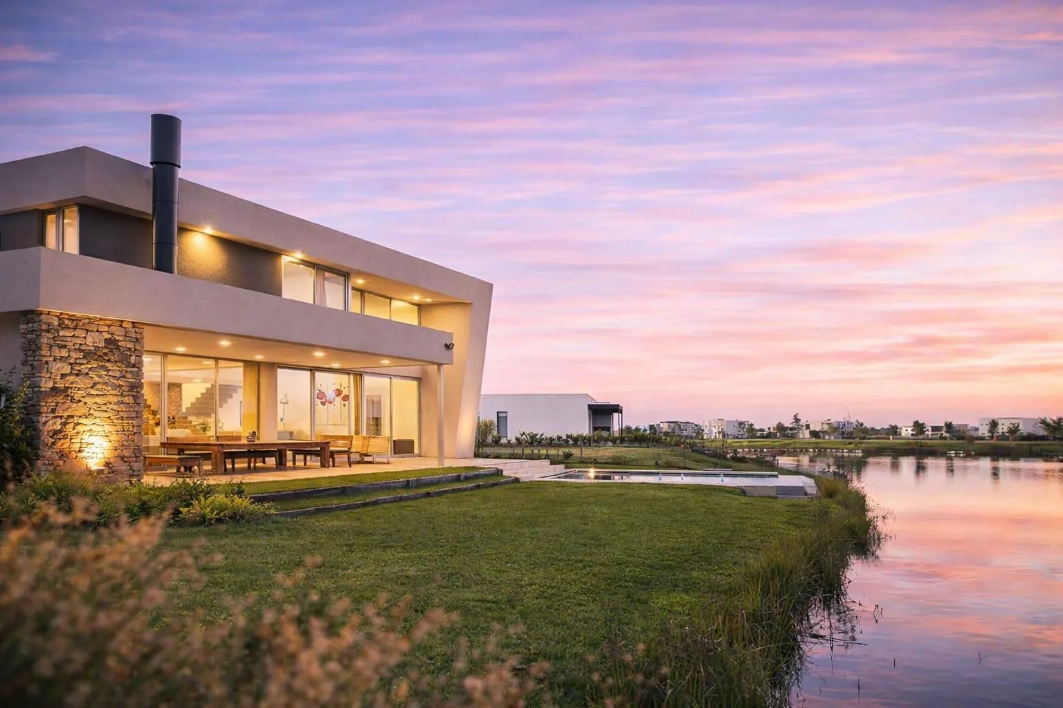Casa al lago en Muelles, Puertos, al atardecer: la galería iluminada y el lago reflejando el cielo